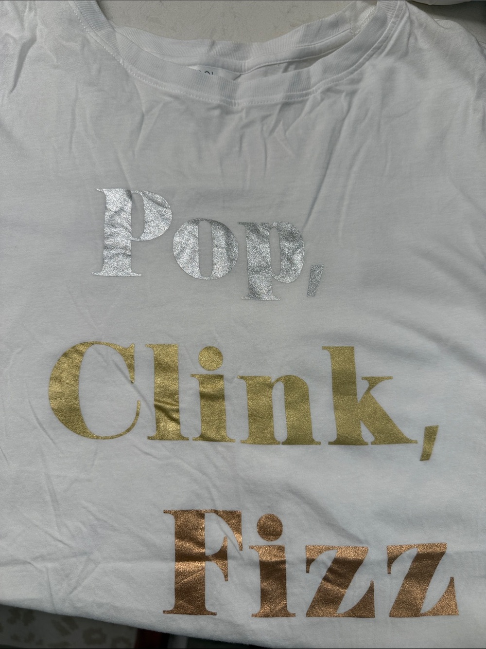 White Graphic Tee with Metallic Gold & Silver Text. Pop, clink , fizz